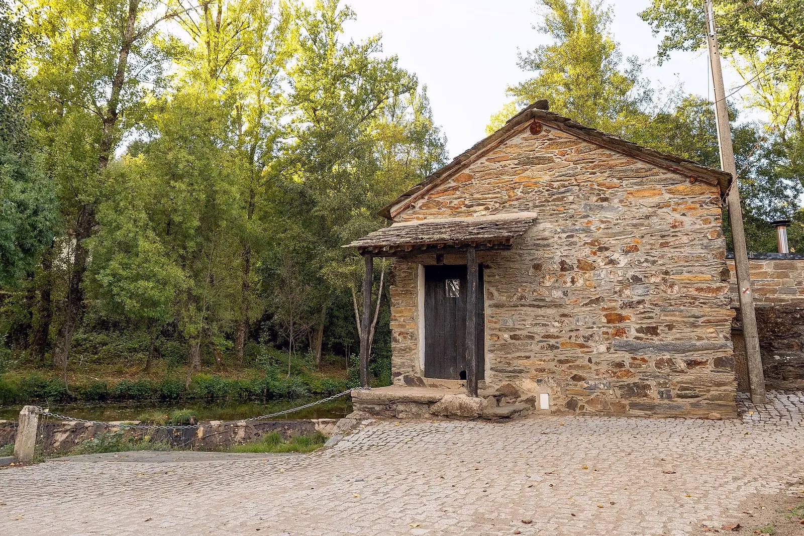 Casa de pedra com alpendre junto à lagoa