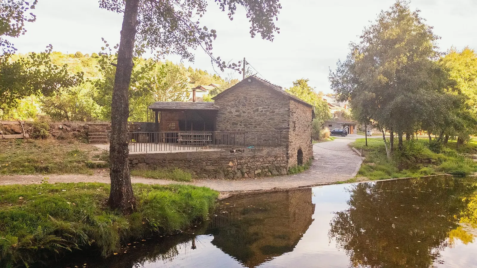 Edifício de pedra junto à ribeira, com o reflexo na água