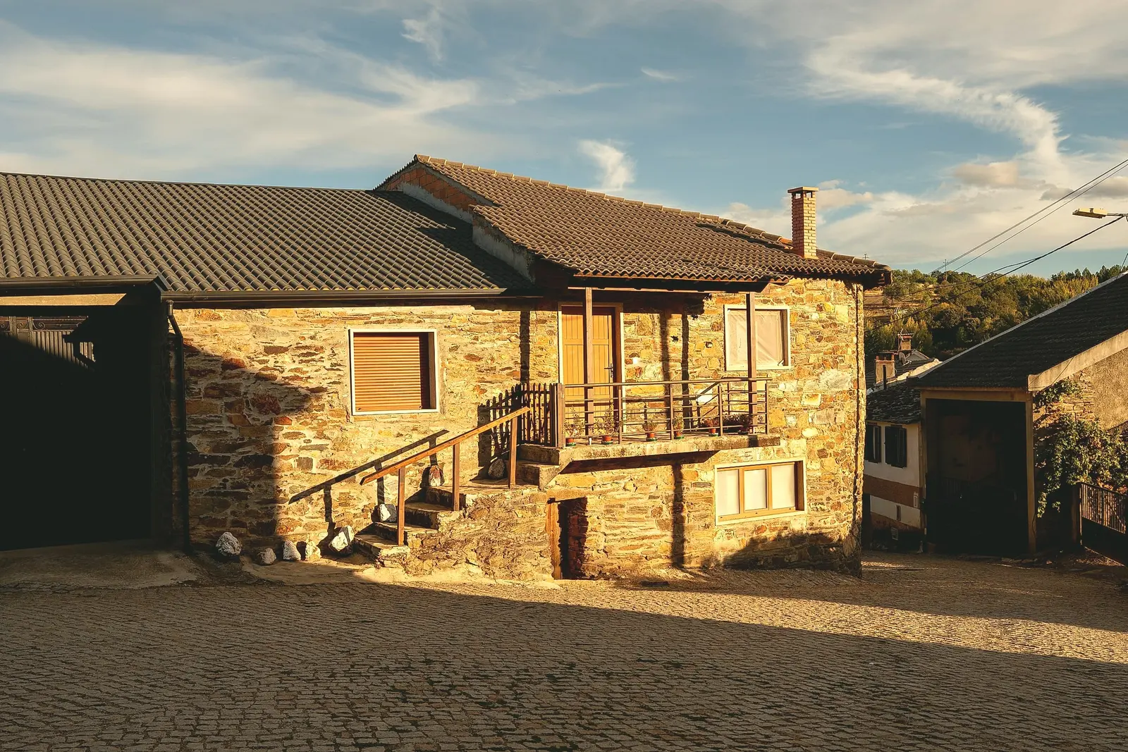 Casa tradicional em pedra, com varanda de madeira, ao fim da tarde