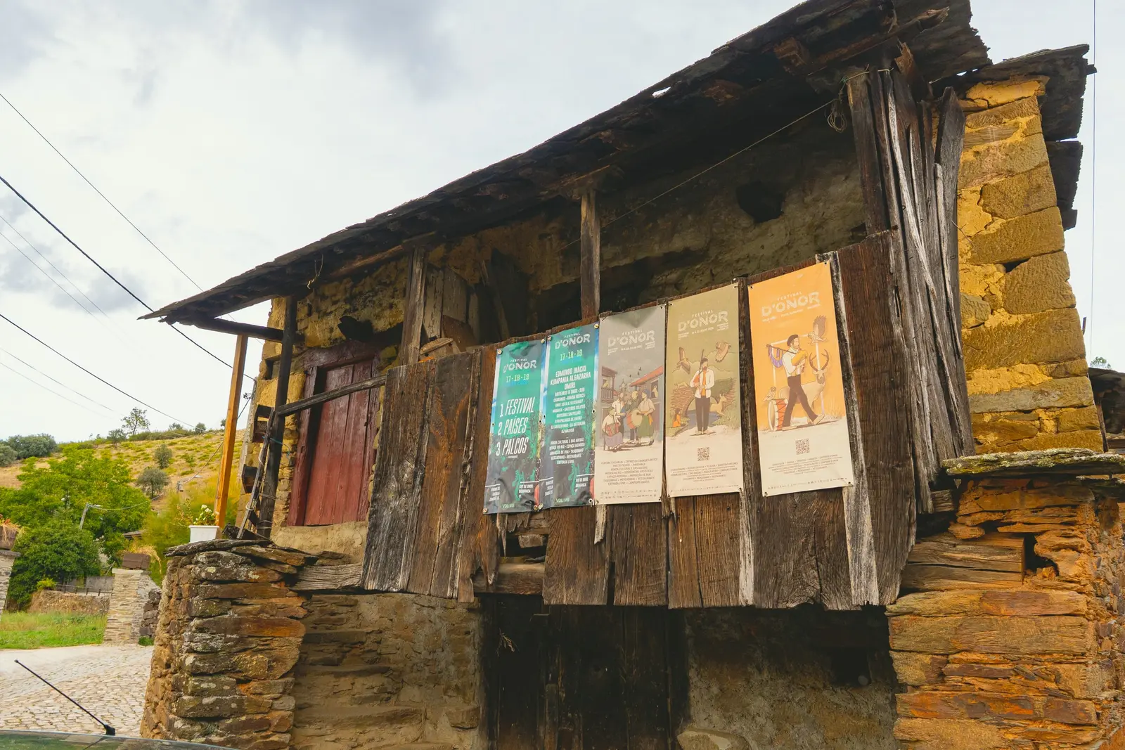 Palheiro de madeira e xisto com cartazes da aldeia