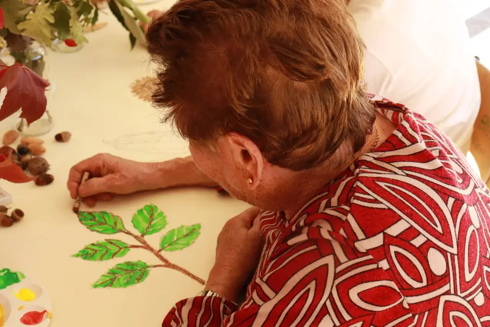 Participante a pintar de verde um ramo de folhas
