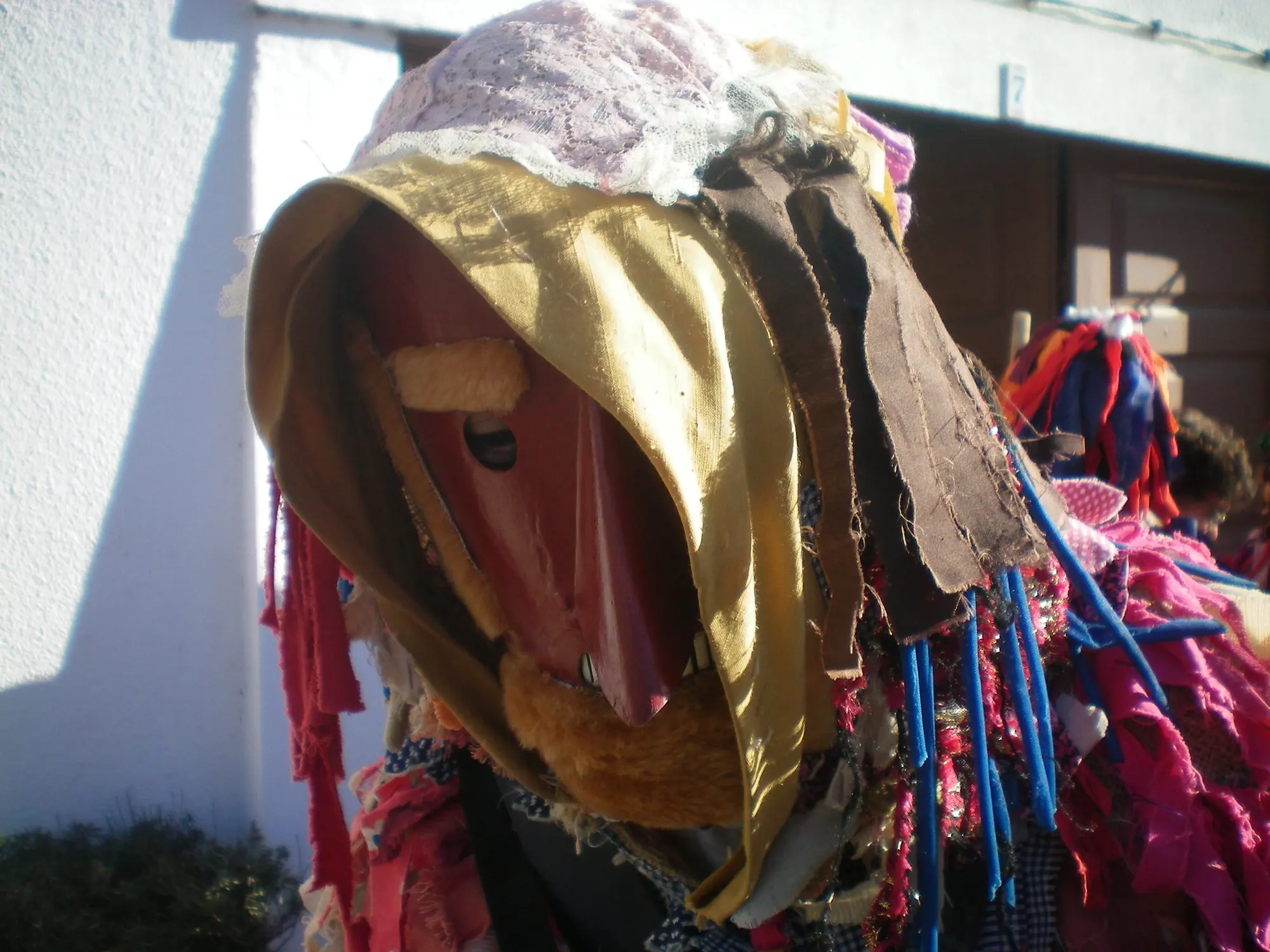Careto de capuz dourado e máscara vermelha, com tiras de tecido às cores